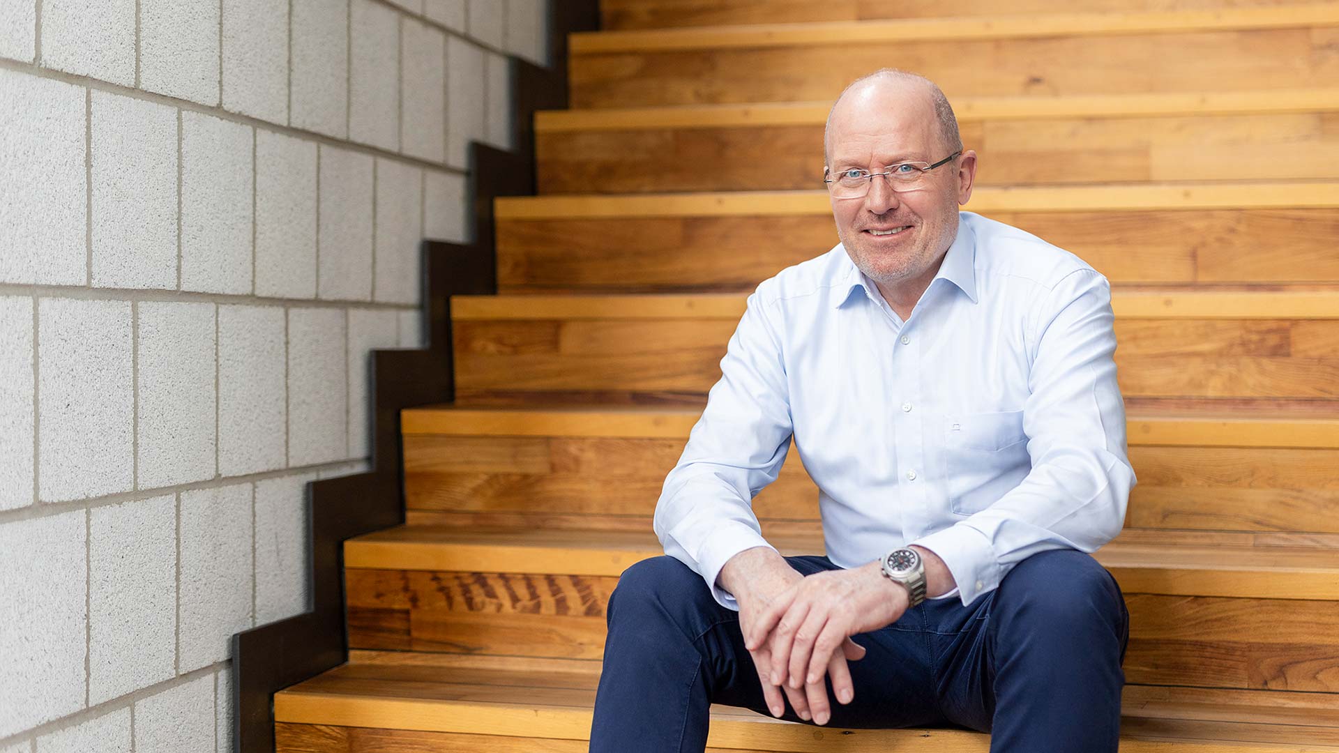 Portrait von Olf Clausen sitzend auf einer Treppe aus Holz