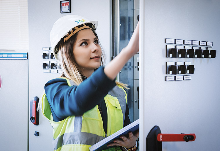 Ingenieurin mit Pad vor einem Schaltschrank
